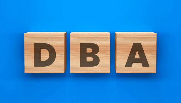 DBA Wooden Blocks:  Three wooden blocks spell out the acronym DBA against a clean blue backdrop. A concept of business, data, and management
