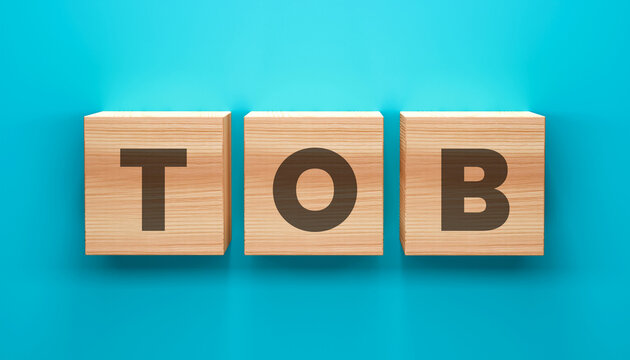 TOB Wooden Cubes Arrangement: A top-down shot of wooden blocks arranged with TOB letters laid on a cyan surface. A symbol of thought, opportunity, or building blocks. 