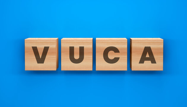 VUCA Concept: An abstract visual of wooden blocks spelling out the acronym VUCA, set against a vibrant blue backdrop. Explore the concepts of Volatility, Uncertainty, Complexity, and Ambiguity.