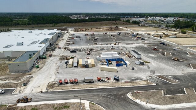 Aerial view of the construction site at Foundry Lane featuring a large warehouse building, heavy machinery, and shipping containers World Golf Village, Florida, United States.