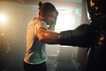 Obraz premium Male athlete boxing in gym for strength training, dedicating to fitness and healthy lifestyle