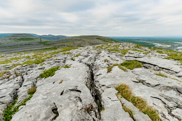Naklejka premium Limestone pavement landscape in Burren National Park, County Clare, Ireland. Wild karst scenery on the Wild Atlantic Way with views across the Irish countryside.