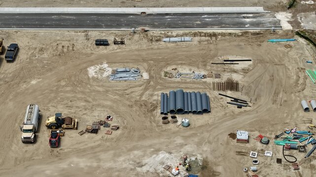Aerial view of the construction site at Foundry Lane featuring heavy machinery, large drainage pipes, and building materials on a dirt lot World Golf Village, Florida, United States.