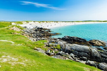 Naklejka premium Rocky shoreline and turquoise water at Dogs Bay near Roundstone, Connemara, County Galway. Scenic white sand beach on the Wild Atlantic Way beside Gurteen Bay, Ireland