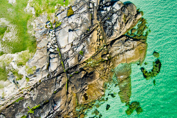Naklejka premium Rocky shoreline at Dogs Bay near Roundstone, Connemara, County Galway, Ireland. Scenic Atlantic coast with granite boulders and clear water on the Wild Atlantic Way.
