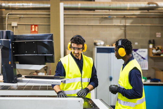 Factory workers operating cnc machine in lumberyard