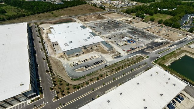 Aerial view of the industrial construction site at Foundry Lane featuring large white-roofed warehouses and heavy machinery in World Golf Village, Florida, United States.