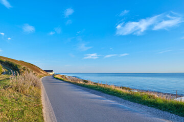 Obraz premium Coast, horizon and road in nature for commute or travel to remote destination in summer season. Asphalt street, ocean and wallpaper with direction, path or route outdoor for landscape or scenic view