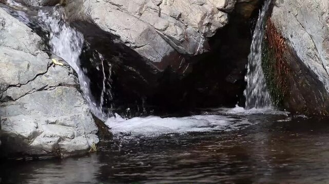 aguas cristalinas fluyen en un torrente natural entre dos grandes rocas en un arroyo de bosque