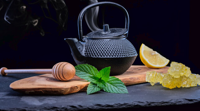 Rustic tea set with a black cast iron teapot, fresh mint, lemon, and honey. Elegant moody food photography, perfect for kitchen decor and wellness content.