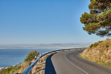 Obraz premium Landscape, blue sky and road by ocean for travel, tourist destination and journey outdoor. Empty, background and street with scenic route, highway and seaside for vacation, trip and holiday by coast
