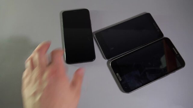 Close-Up Hand Picking Up Orange and Smartphones One by One