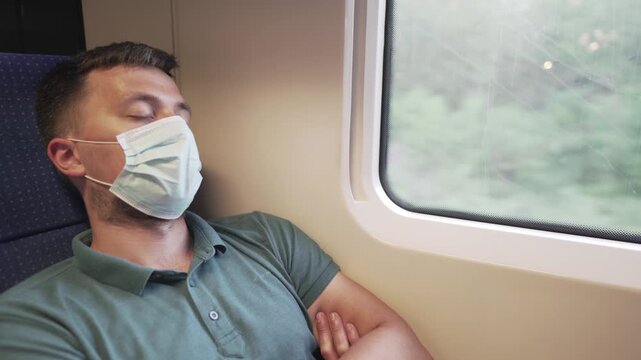 Tired sleeping train commuter wearing PPE face mask for safety. Concept travel during pandemic. Protective medical mask during the trip. Medical respiratory bandage face in transport.