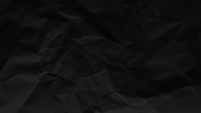 Stop motion crumpled black paper texture. Abstract loop background with dynamic wrinkled folds and organic movement. Dark grunge monochrome seamless animation.