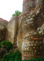 Wysokie, surowe mury twierdzy Narikala w Tbilisi uchwycone z bliska pokazują historyczną strukturę kamienia i skalistego ukształtowania terenu. © Adam