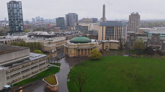 Overcast skies above University of Toronto campus revealing Convocation Hall with green roof, modern skyscrapers and downtown financial district skyline in Canada