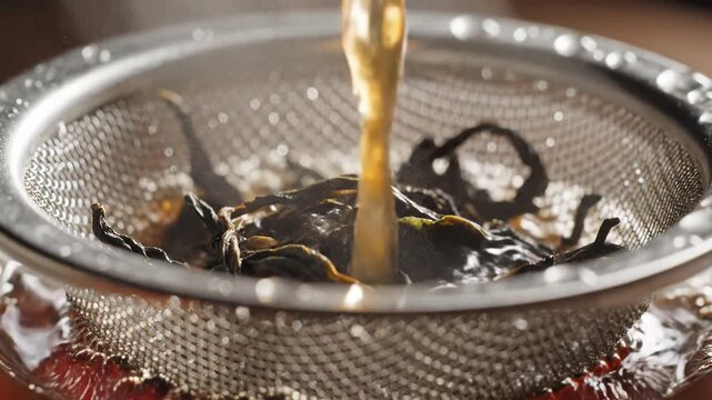 Close up of hot tea being poured through a strainer.
