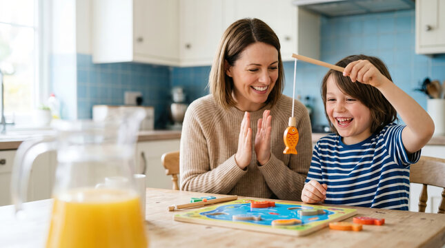 Woman and kid playing wooden fishing table game in bright home kitchen. Happy mother cheering for son catching fish toy. Educational leisure hobby for childhood development at home.