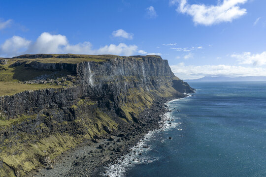 Aerial view of the dramatic cliffs and rocky shoreline of Talisker Bay Beach meeting the turquoise waters of the Atlantic Ocean Isle of Skye, Scotland, United Kingdom.