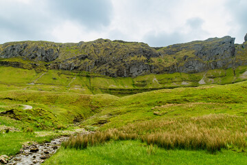 Obraz premium Gleniff Horseshoe in County Sligo, Ireland, with rolling grassland beneath steep limestone mountains and bright clouds. A scenic drive through one of Irelands classic valleys.