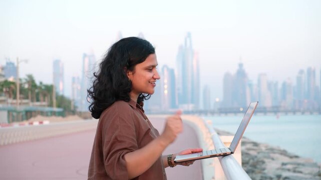 Businesswoman attending online meeting outdoors with Dubai skyline and remote work lifestyle video