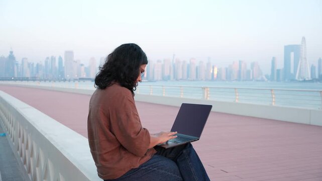 Professional woman working outdoors during luxury workation with Dubai waterfront skyline video