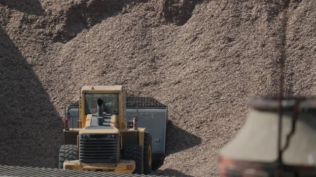 Large machine moves wood chips at a processing site in daylight