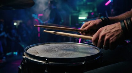 Obraz premium Focused image of hands gripping drumsticks over an aged snare with dust particles visible set against a dark smoky backdrop illuminated by cinematic neon lighting at a dynamic