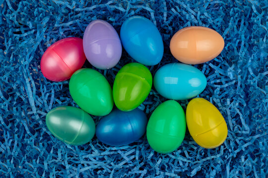 Colorful plastic Easter eggs on blue paper grass