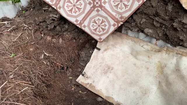 The compost manure pile has a fence made of slate sheets and is covered with pieces of linoleum on the street in the summer cottage