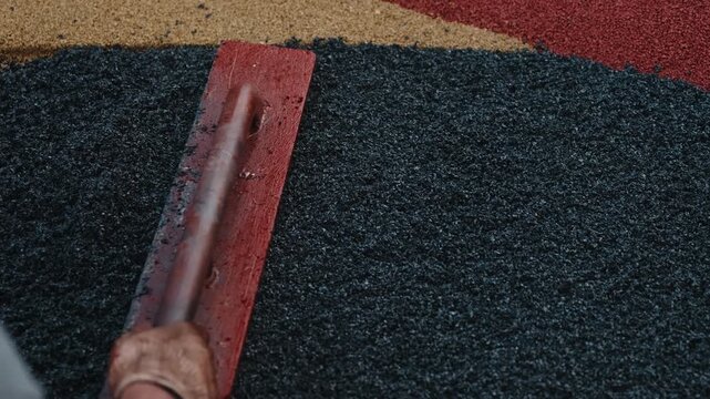 Leveling recycled rubber crumb coating on sports playground close up