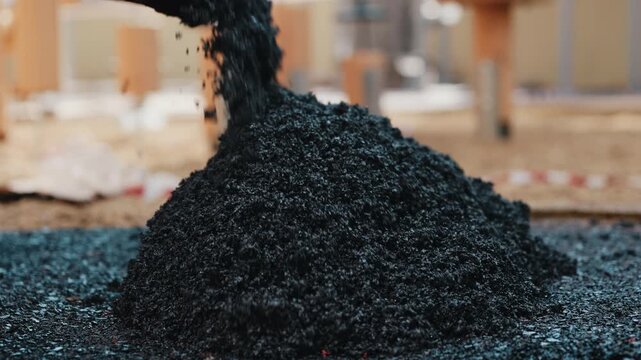Pouring rubber crumb mixture onto playground surface during installation close up