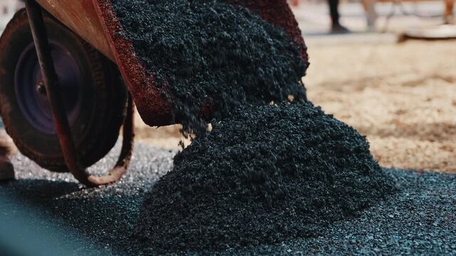Pouring recycled rubber crumb onto playground surface during installation close up