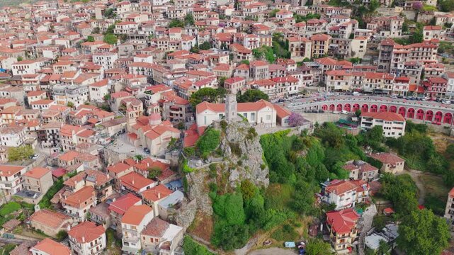 Aerial drone footage capturing the picturesque mountain town of Arachova, Greece, revealing its traditional stone houses with red-tiled roofs, historic churches, and the iconic clock tower