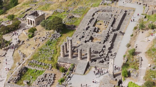 Aerial view of the temple of Apollo and the treasury of the athenians ruins with tourists walking around the archaeological site of Delphi, a famous Unesco world heritage site in Greece