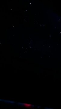Inside view of an airplane with a fiber optic starlight ceiling twinkling in a dark interior, creating a calm, luxurious night sky atmosphere.