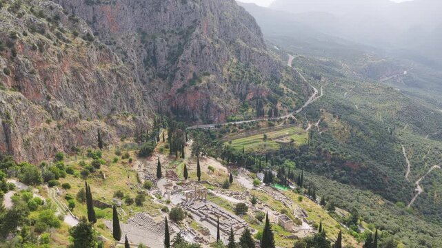 Scenic aerial view of the archaeological site of Delphi, showing the temple of Apollo and the ancient theater nestled on the slope of mount Parnassus in Greece on a hazy day