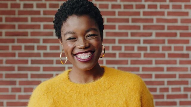 Face, confidence and black woman with laugh by brick wall, funny memory and remember joke for smile. Portrait, good mood and female person with reaction for comic experience, humor and happiness