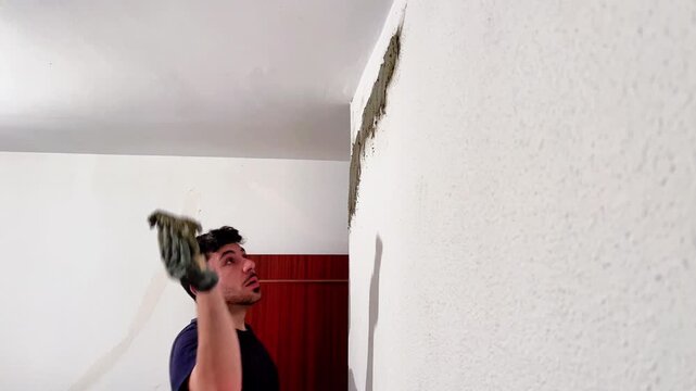 Handyman plastering and renovating a damaged interior wall in a house