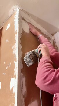Person using electric sander for wall renovation and home improvement project