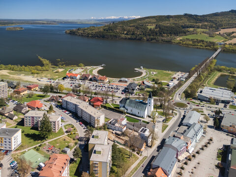 Aerial view of the Roman Catholic Church of Saints Simon and Jude, the Orava Reservoir, and residential buildings in Namestovo, Zilina Region, Slovakia.