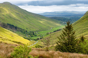 Obraz premium Glengesh Pass winding through a green mountain valley in County Donegal, Ireland. A scenic road landscape of the Wild Atlantic Way and remote Irish highlands.