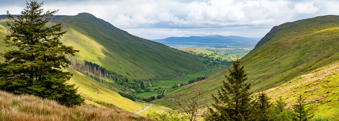 Obraz premium Glengesh Pass winding through a green mountain valley in County Donegal, Ireland. A scenic road landscape of the Wild Atlantic Way and remote Irish highlands.