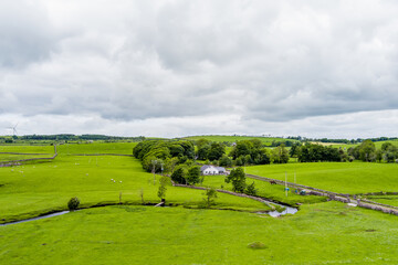 Obraz premium Rolling green meadows with sheep, stone walls and wind turbines near Donegal, Ireland. A rural landscape combining farmland, open scenery and renewable energy.