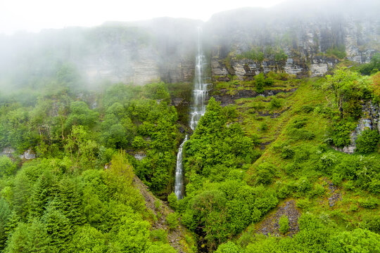 Devils Chimney Waterfall dropping through misty cliffs near Glencar Lough, Ireland. Dramatic cascade in the lush northwest landscape of County Sligo and Leitrim.