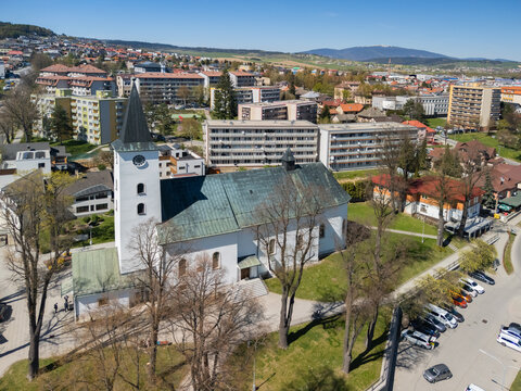 Aerial view of the Roman Catholic Church of Saints Simon and Jude with its white facade and tall steeple surrounded by residential buildings in Namestovo, Zilina Region, Slovakia.