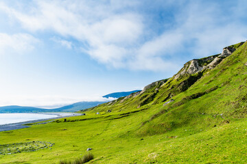 Obraz premium Southern Keel Beach on Achill Island, County Mayo, Ireland, with green coastal slopes above the shore. This image shows the quieter grassy edge of the beach.