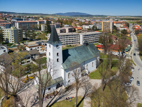 Aerial view of the Roman Catholic Church of Saints Simon and Jude with its white tower and green roof overlooking the town and distant mountains in Namestovo, Zilina Region, Slovakia.