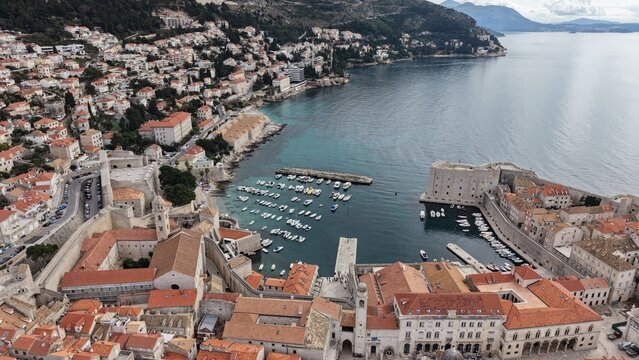 Aerial view of Dubrovnik Old Town and its medieval city walls. Cinematic shot of the UNESCO World Heritage site featuring limestone streets and terracotta roofs in Croatia.