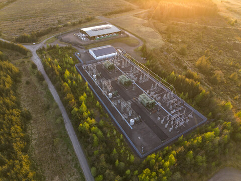 Aerial view of Eaglesham moor substation with electrical transformers and industrial buildings surrounded by dense forest at sunset Kilmarnock, Scotland, United Kingdom.